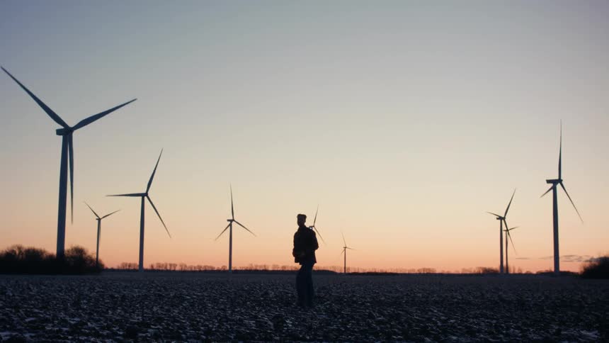 A person walking on a modern wind farm