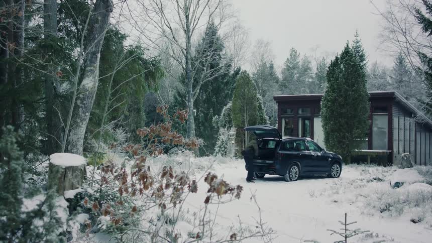 Person removing an accessory from the trunk of a car in an outdoor environment covered in snow