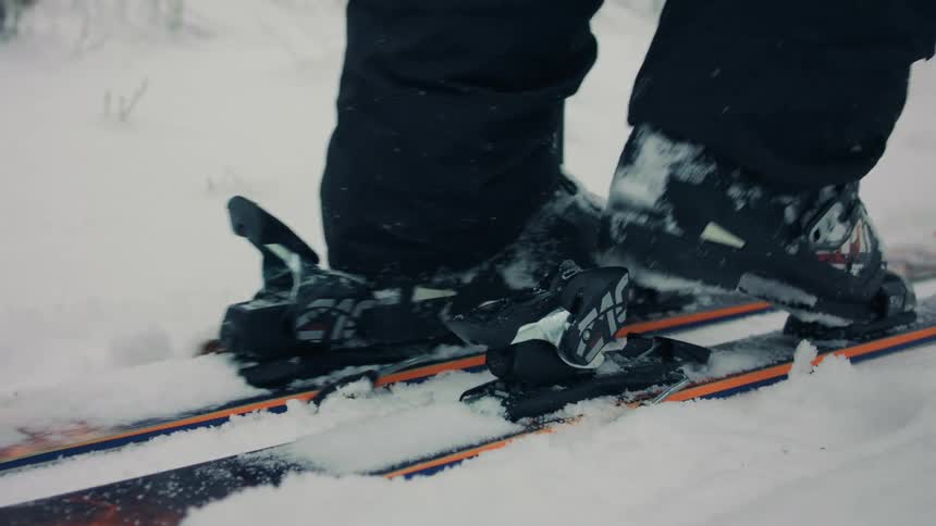 Skier steps puts on snow skis and then skies away