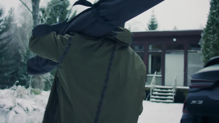 A man taking out his hiking equipment out of the car and walking into the snowy woods