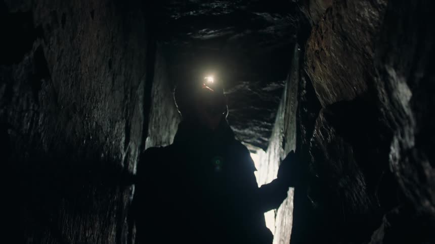 Man walking inside a cave with a cellphone flashlight