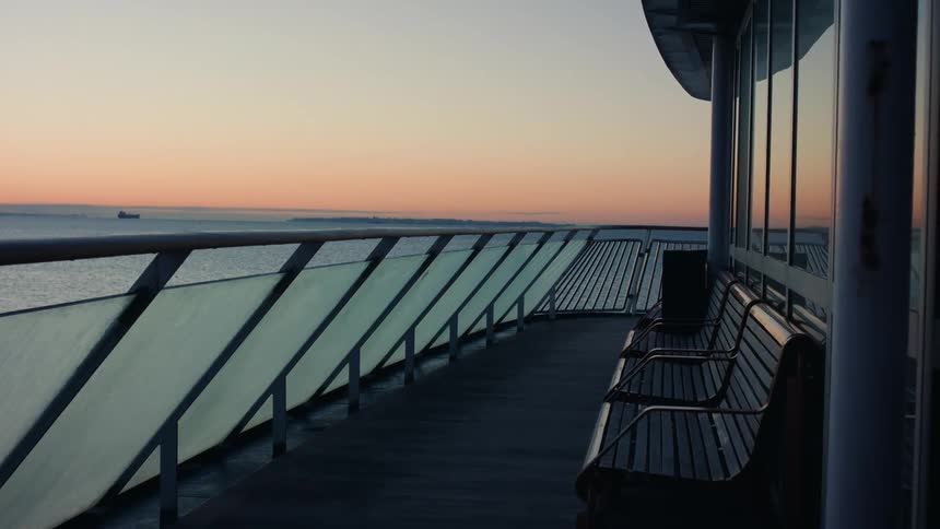 The balcony of a building facing the beach during sunset
