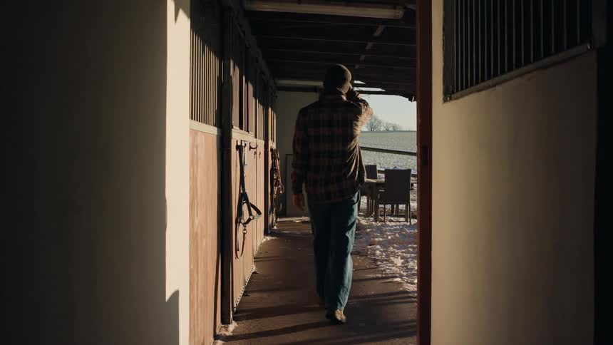 A person walking on a path next to a house and wearing cold clothing