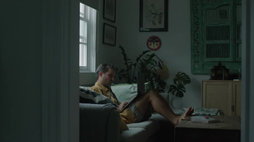 A man working on his laptop relaxed on the sofa