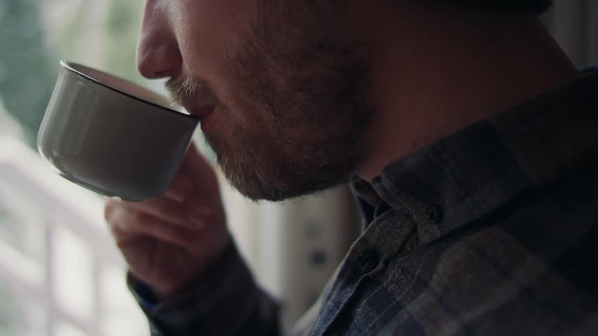 Closeup of a mans mouth sipping from a cup