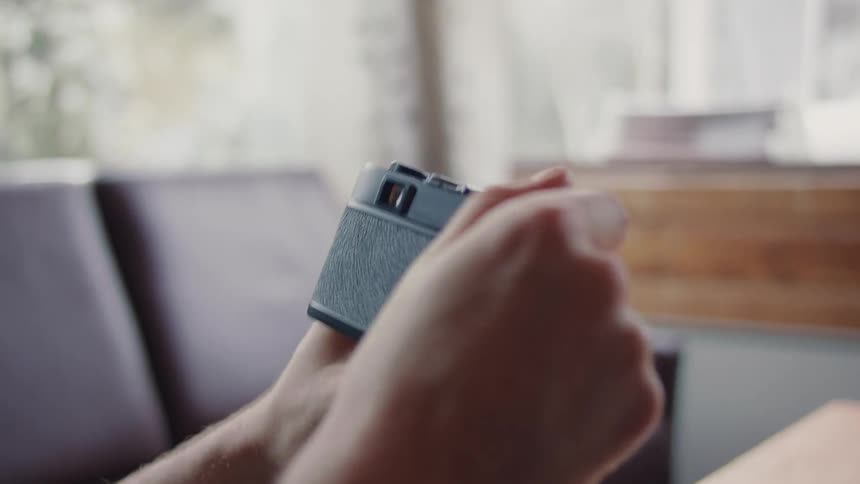 Closeup of a mans hands opening a vintage camera and adjusting the internal film