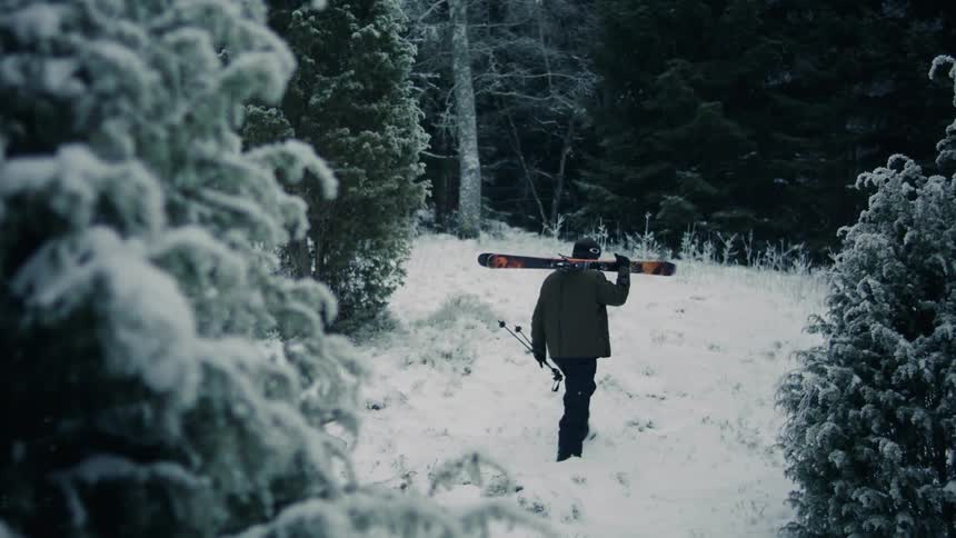 Man walking with his ski equipment through a snowcovered forest