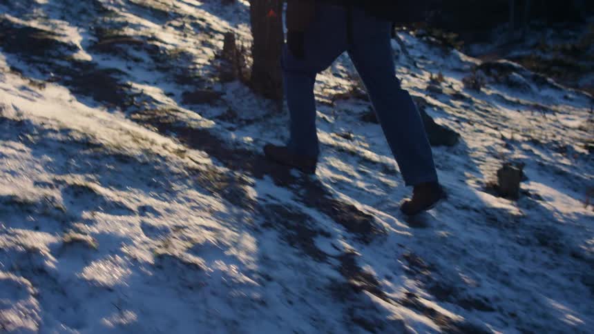 Closeup of a persons legs walking in a natural environment with snowcovered ground