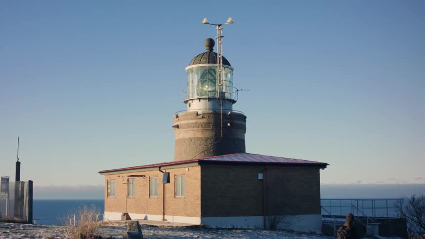 Hiker walks past lighthouseduring winter