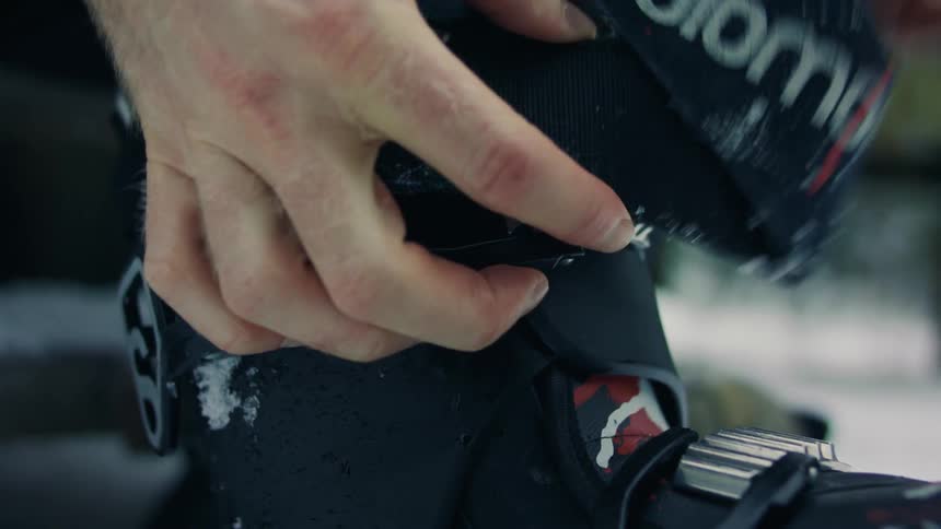 Closeup of a mans hands adjusting the ski boot