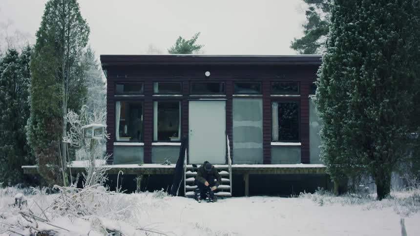 A sitting on the stairs of a cabin in a snowy landscape