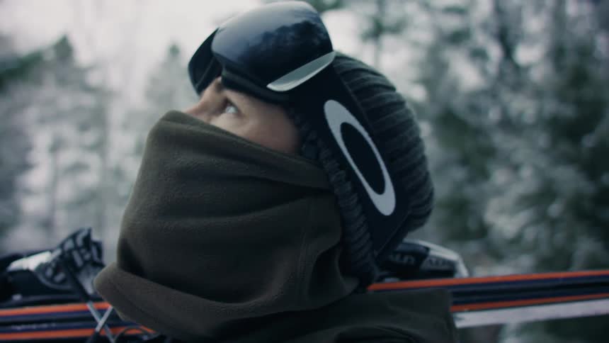 A person holding sports equipment in the forest during winter