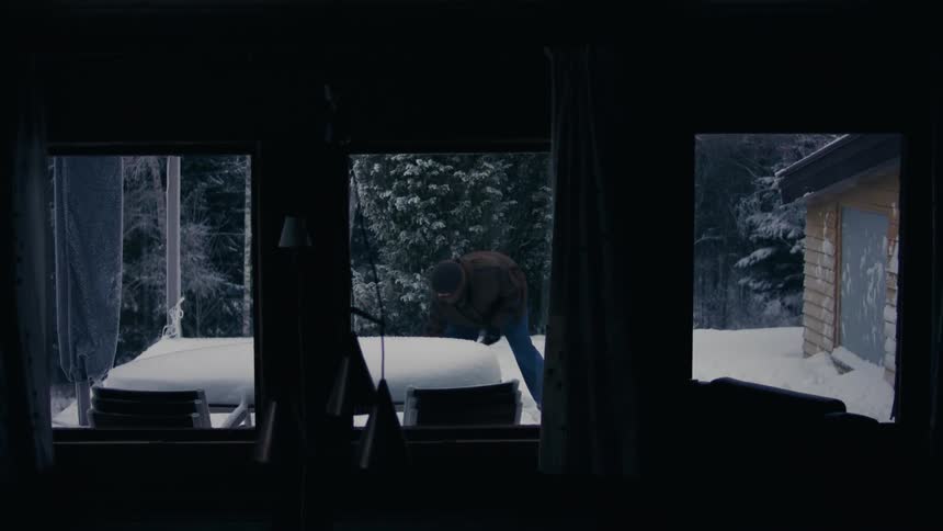 Man shovels snow near house during winter day