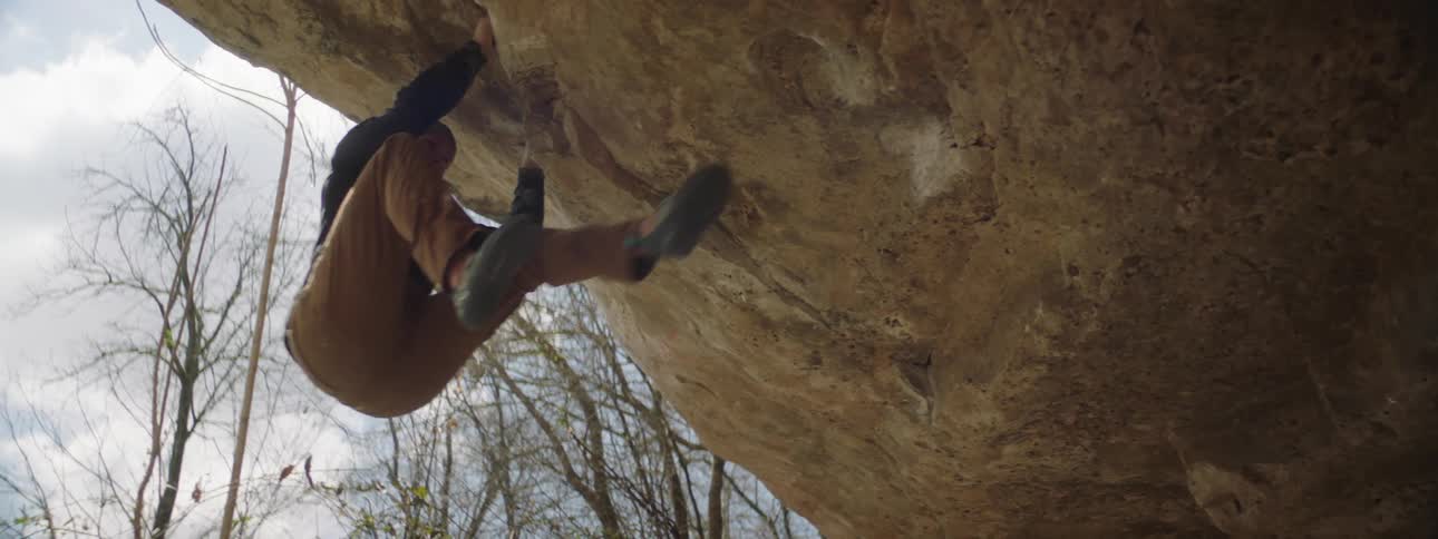 A man rock climbing on a large boulder outdoors