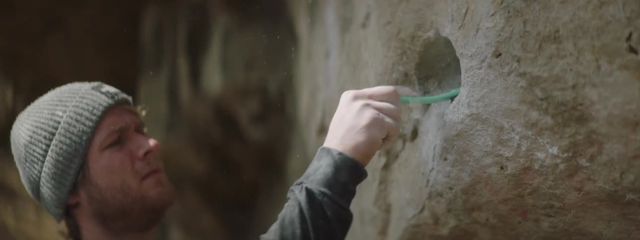 An archaeologist brushing a hole in a rock