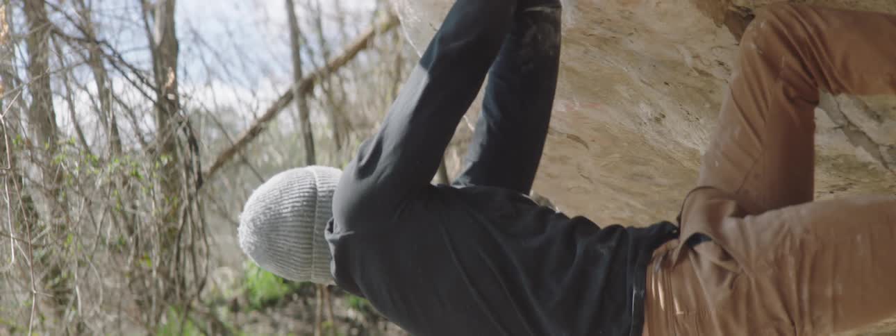 A young man is rock climbing on an early spring day