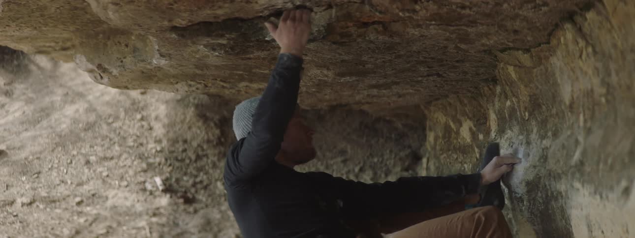 A climber hanging from an overhanging rock