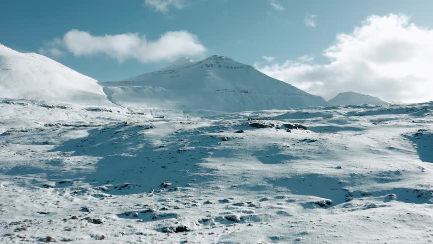 Aerial view flying over snow covered areas with mountains in the distance