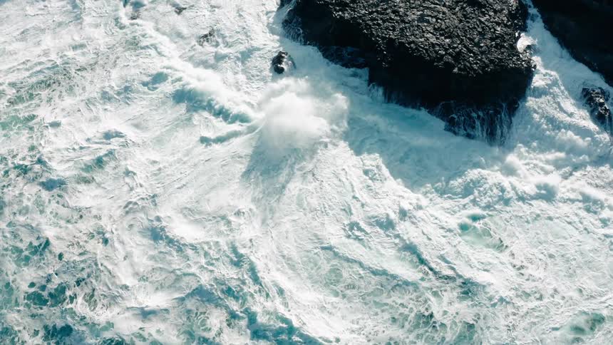 Aerial view of ocean waves breaking against the rocks