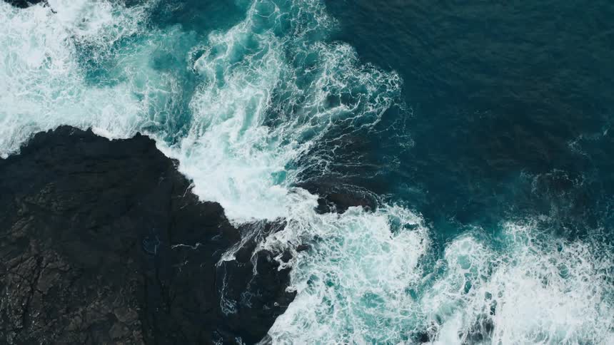 Aerial view of waves breaking against the rocks in the coast