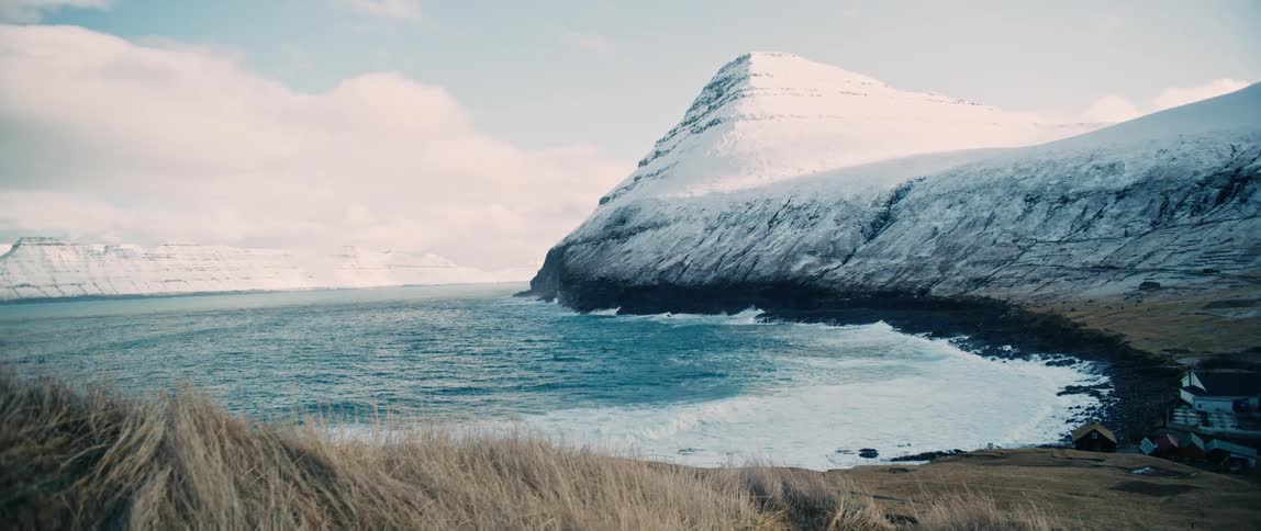 A beach in a region with a huge mountain with its top covered in snow
