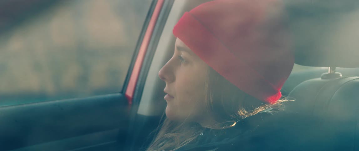 A young woman is sitting inside a car pensive