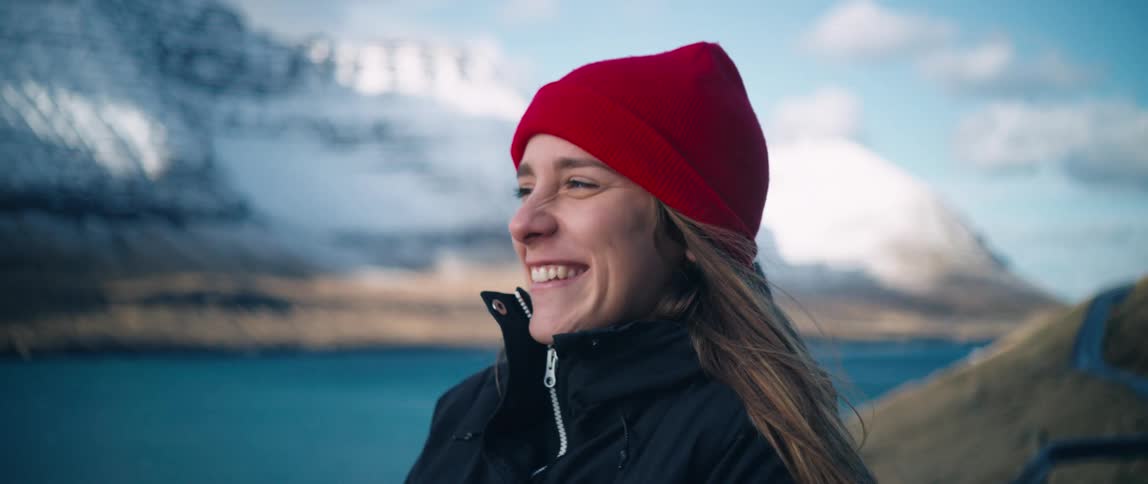 A young woman smiles at the camera in front of a mountain