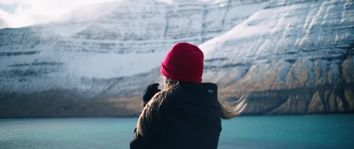 A woman gazes at a glacier while moving her hand to keep it warm