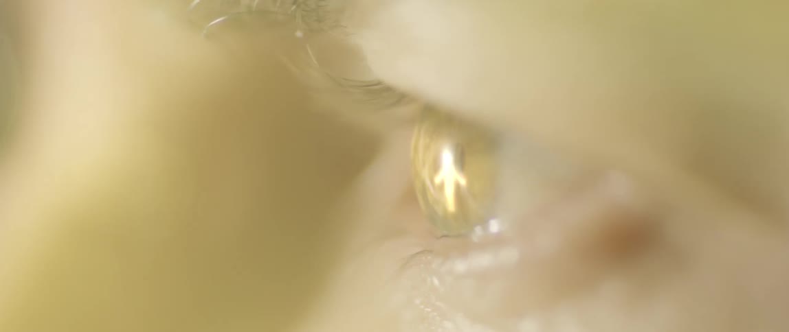 An eye opens showing a reflection of a bright figure