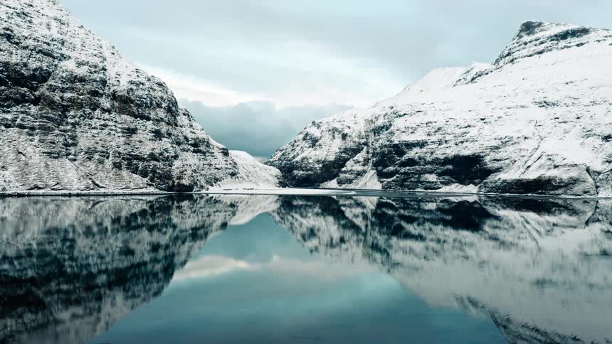 Still lake surrounded by snow capped mountains