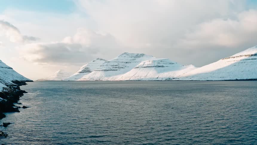 View of the moving sea with a chain of snowcovered mountains around