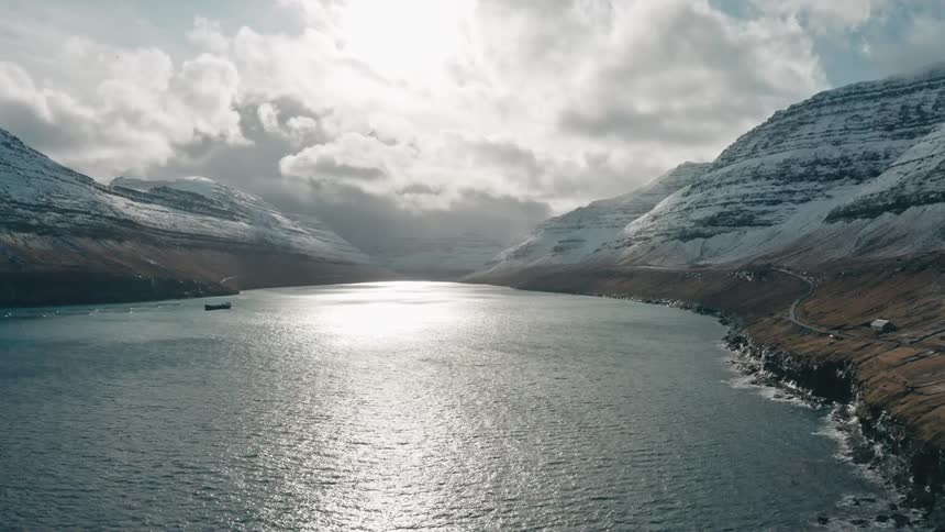 Placid scene of a river surrounded by snow covered mountains at evening