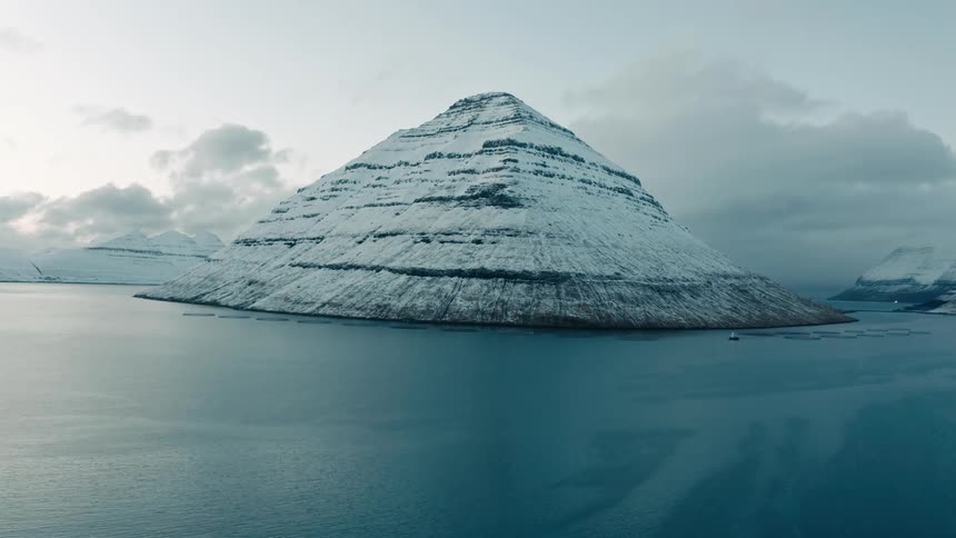 Aerial of snowy mountains in the arctic sea during sunset