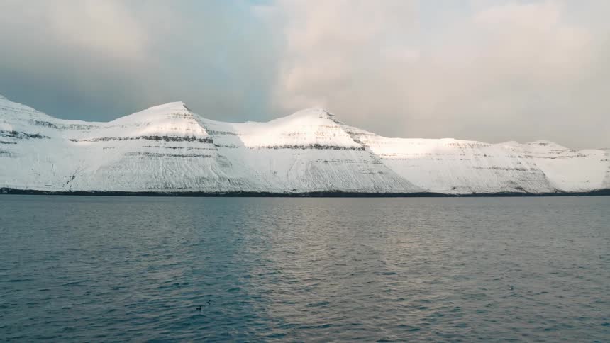 Aerial view flying over water towards arctic mountains