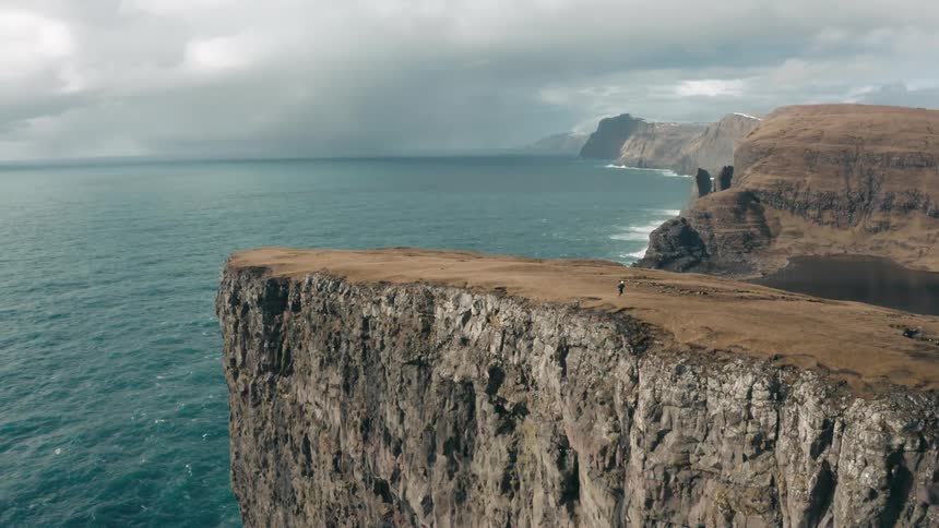 Aerial view of a person jogging near a cliff next to the ocean