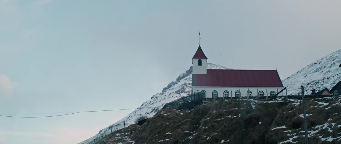 A church sits on a snowy hill in a rural area