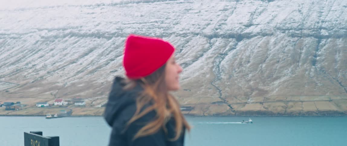 A young woman smiles while viewing a mountain range and a river from an overlook