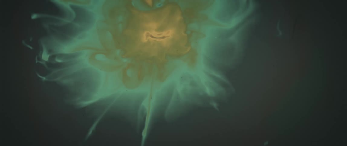 Filmy green mixture with yellow center contracts in dark liquid