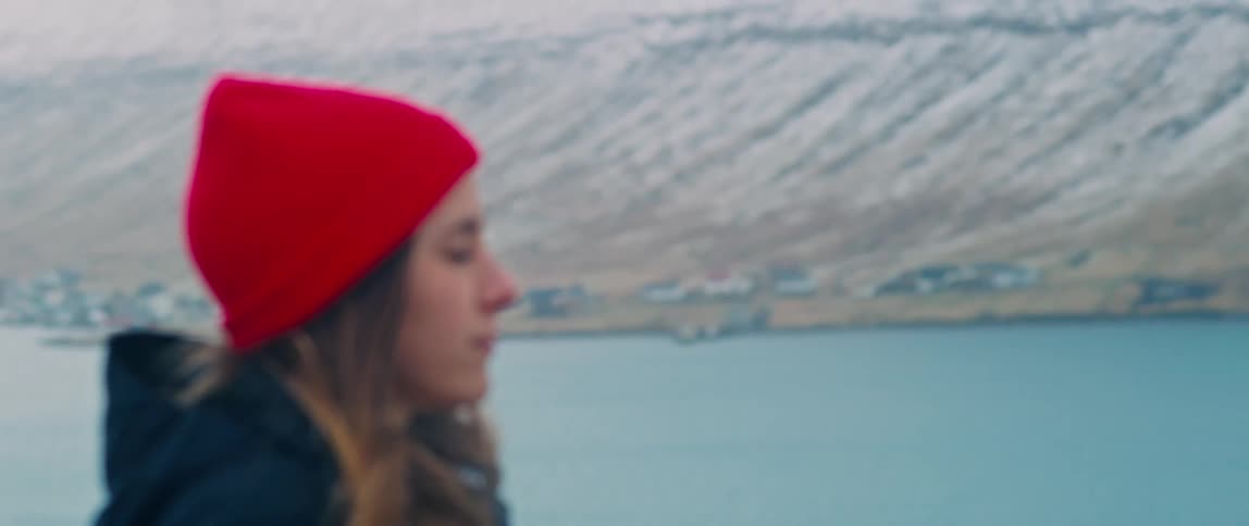 Portrait of a woman with a cap closing her eyes serenely amidst nature and next to the sea