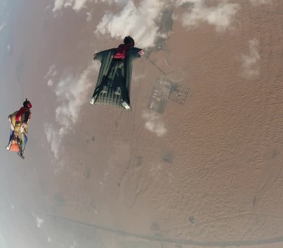 Aerial view of skydivers wearing wingsuits flying over the landscape