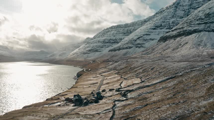 Panorama of snowcovered mountain range by a lake on a cloudy day