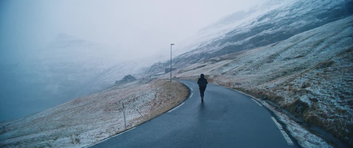 A person walking on a deserted country road during a blizzard