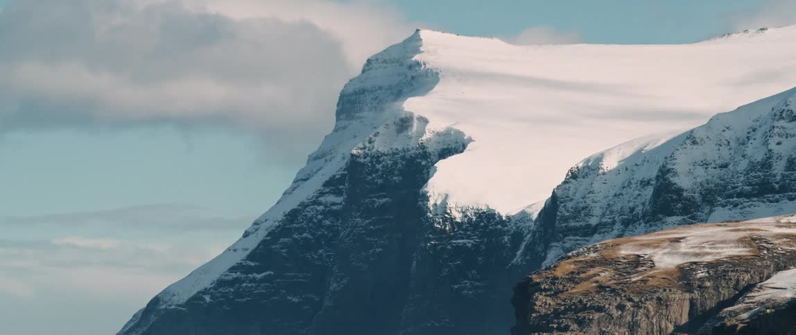 A huge mountain covered in snow with its peak illuminated by sunlight