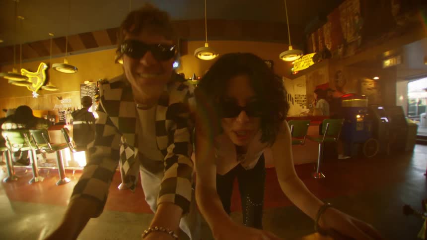 A man and a woman wearing sunglasses are at a gaming table in a bar and are very happy