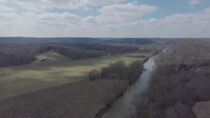 Aerial of a rural field with a small river during the day