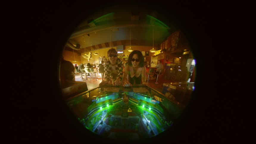 A man and a woman are playing pinball at a table