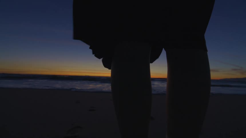 The legs of a person who is standing on a beach one morning and watching the sea