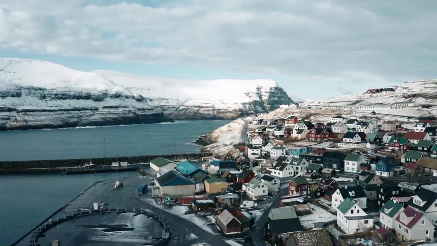 A small housing village sits on a river shore on a cloudy winter day