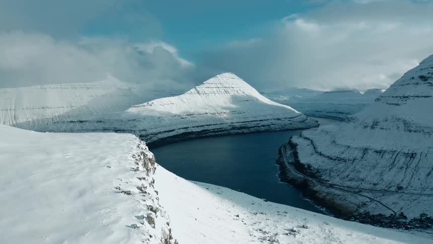 Panorama of a mountain range surrounding a river and covered in snow