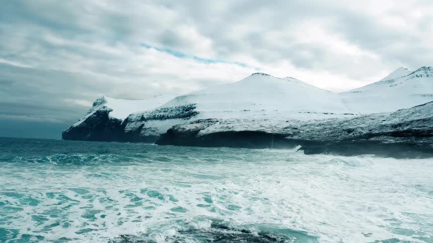 Waves crash against the mountains